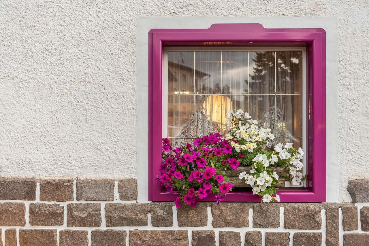 A window with a purple frame and a brick wall below.