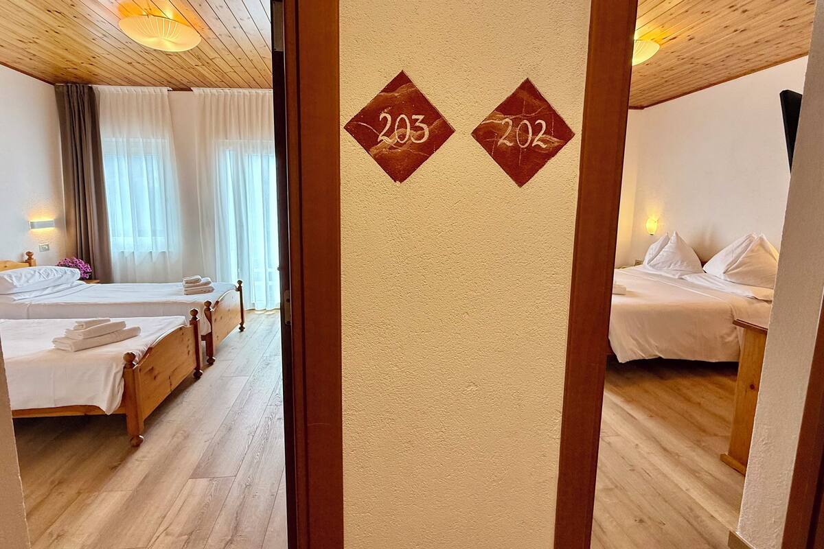 Een hotelkamer met twee bedden, houten vloeren en een muur met de kamer nummers 203 en 202.