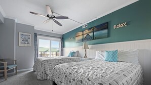 Ein Schlafzimmer mit zwei Betten, einem Deckenventilator, Meerblick und einem Schild mit der Aufschrift 'Relax'.