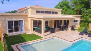 A modern two-story house with a swimming pool, outdoor seating area, and a well-maintained lawn. - Contemporary Design With Lots of big Windows (Sosúa)