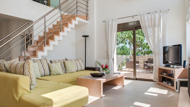 A modern living room with a yellow sofa, a coffee table, a TV, and a staircase. - Countryside villa with private pool and views (Rethimno)