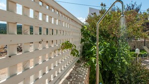 A white wooden fence with a metal structure on the right, surrounded by greenery and a stone wall. - Countryside villa with private pool and views (Rethimno)