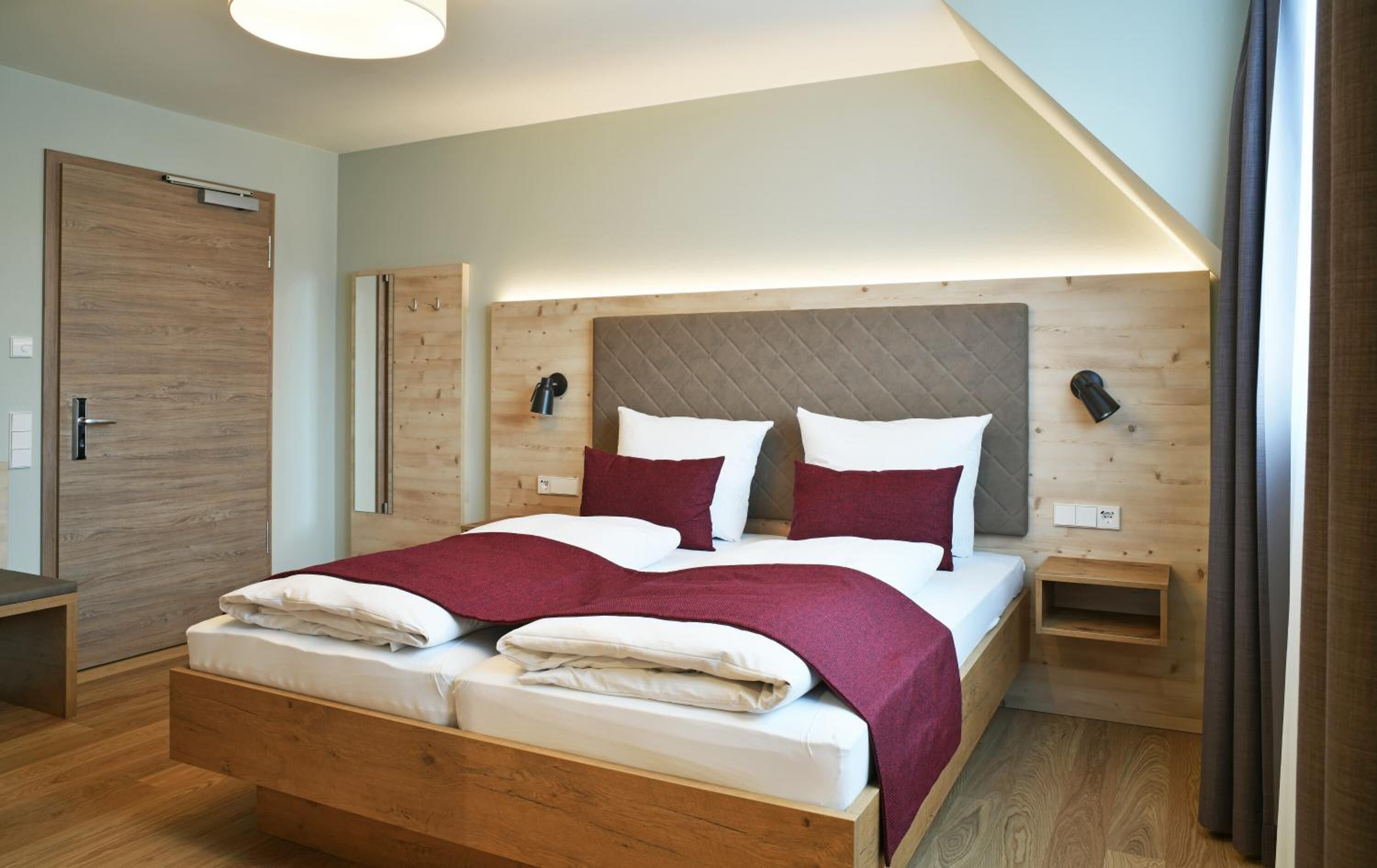A modern bedroom with a wooden bed, a nightstand, and a wall-mounted lamp.