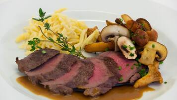 Een bord eten met plakjes rundvlees, champignons en een portie noedels.