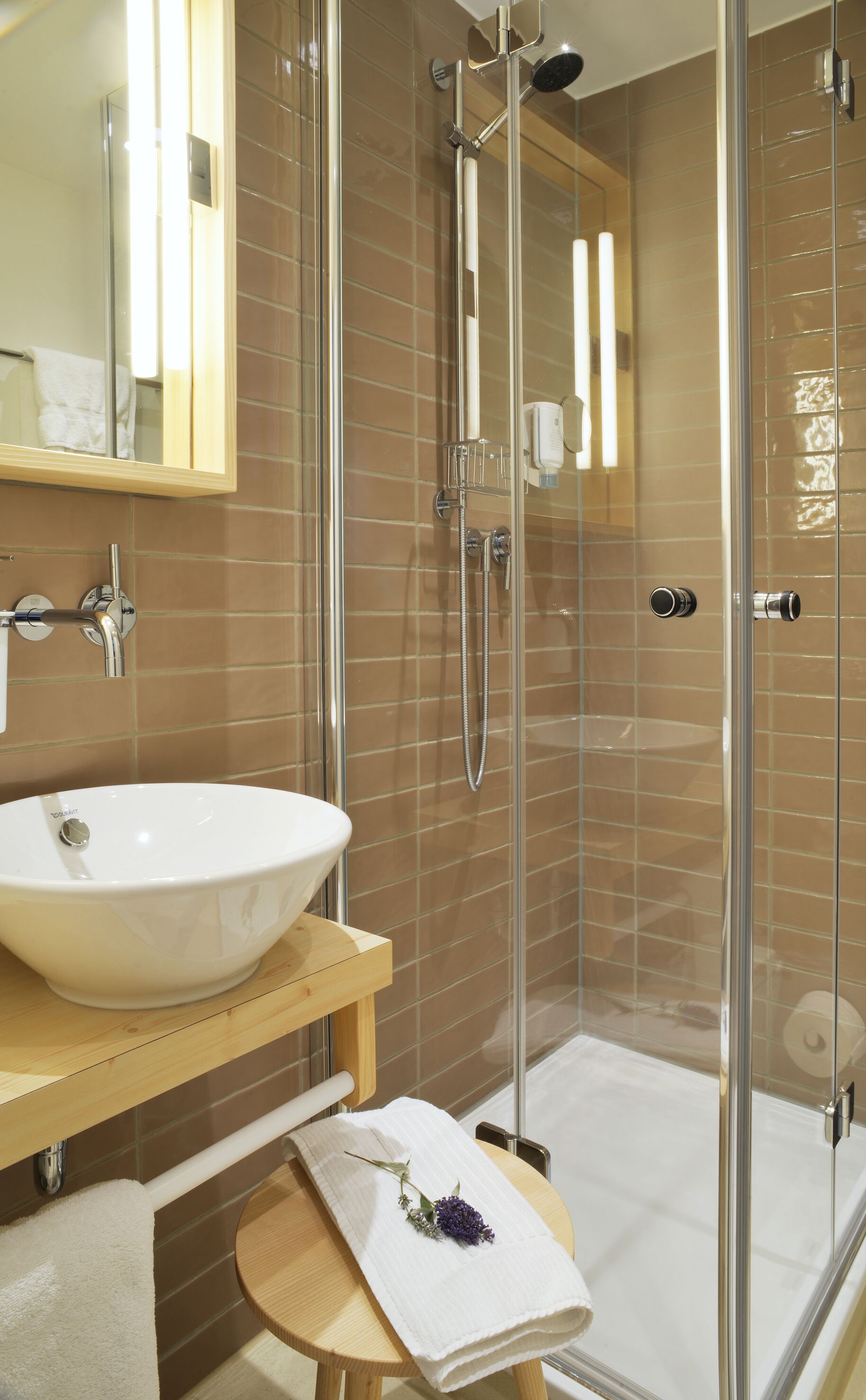 Ein modernes Badezimmer mit einer Glasdusche, einem weißen Waschbecken und einer Holzausstattung.
