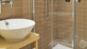 Ein modernes Badezimmer mit einer Glasdusche, einem weißen Waschbecken und einer Holzausstattung.