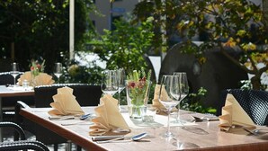 A dining table set with multiple wine glasses, folded napkins, and a small vase with flowers. - Hotel & Restaurant Klosterhof (Gutenzell)
