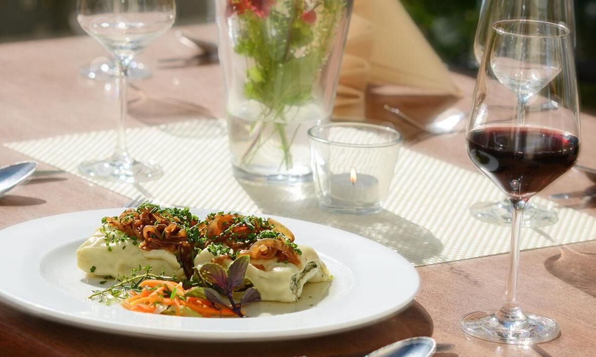 Een eettafel met een bord eten, een glas rode wijn en een kaars.