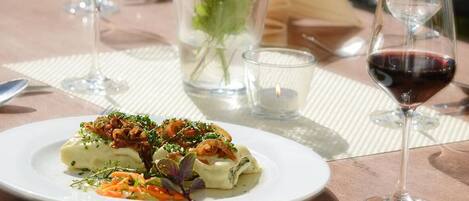 A dining table with a plate of food, a glass of red wine, and a candle.