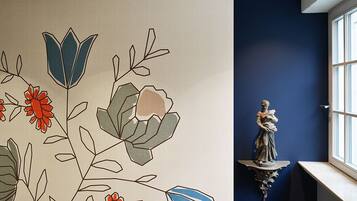 A room with a blue wall, a window, and a decorative wall hanging with floral patterns.