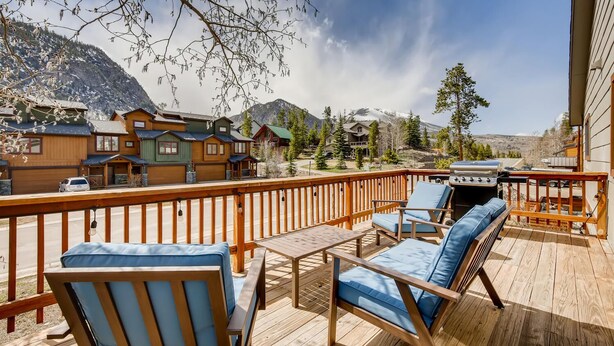 A wooden deck with outdoor furniture, a barbecue grill, and a view of mountain houses. - PET FRIENDLY Condo close to Main Street in Frisco!! (Frisco)