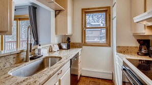 A compact kitchen with granite countertops, stainless steel appliances, and a window with a view of a residential area. - PET FRIENDLY Condo close to Main Street in Frisco!! (Frisco)