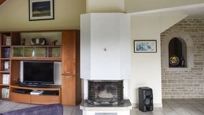 Una sala de estar con chimenea, vigas de madera, un televisor y una chimenea de piedra.