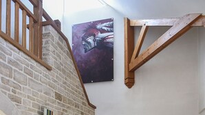 Una escalera con barandillas de madera que conduce a una puerta, una pared de ladrillo y una ventana con vistas al exterior.