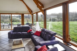 A spacious living area with a large window, a sofa set, and a chessboard.