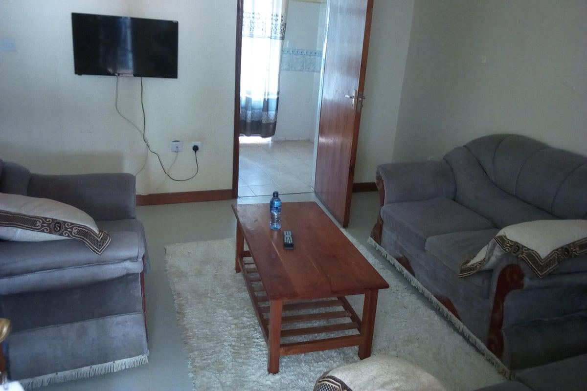 Ein Wohnzimmer mit zwei grauen Sofas, einem Holztisch und einem flachbildfernseher an der Wand.