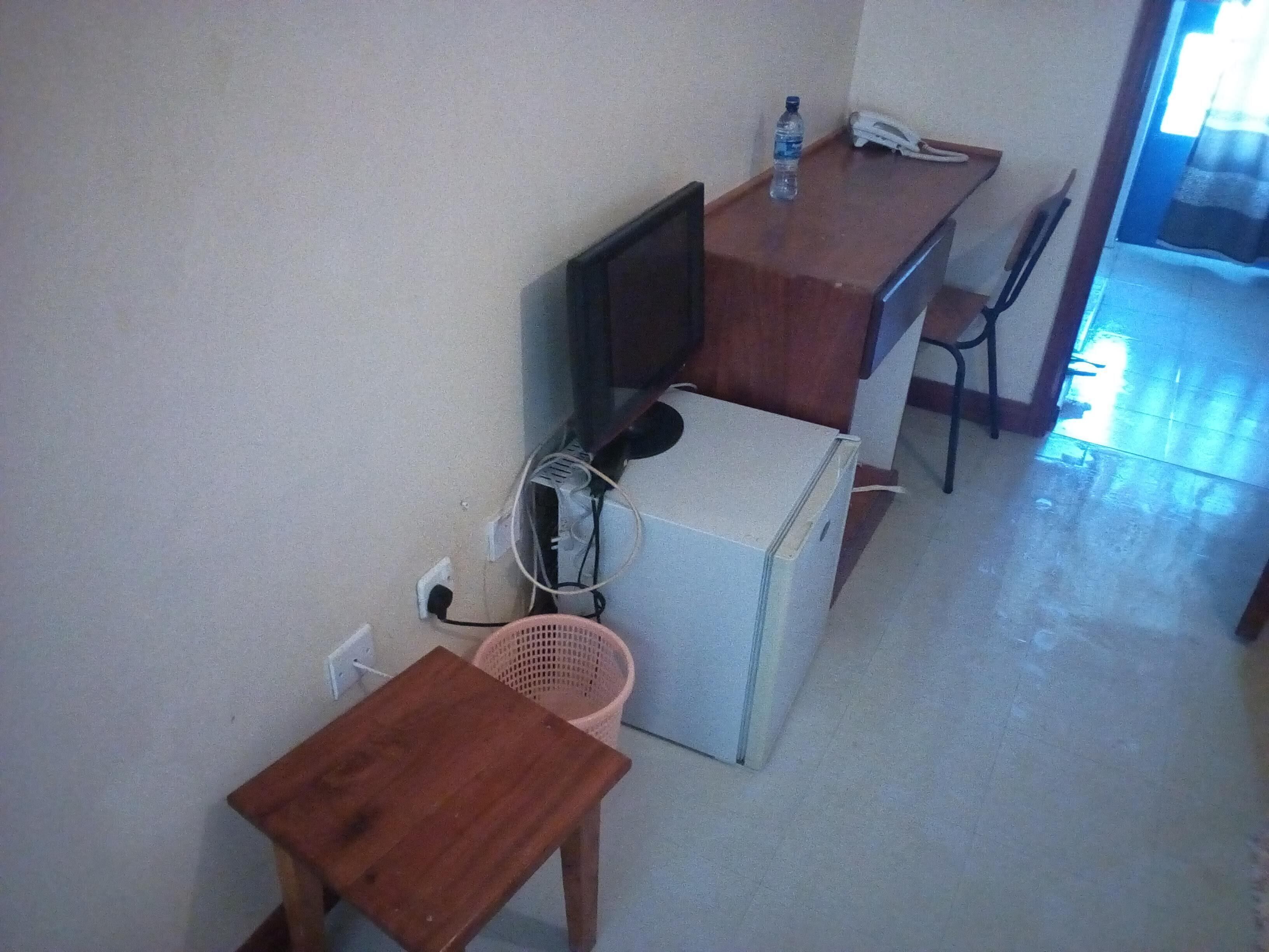 A small kitchenette with a refrigerator, a microwave, a sink, and a wooden table.