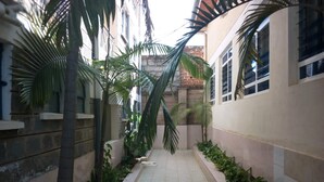 A narrow corridor with tiled flooring, flanked by walls with windows and potted plants. - Kitui Premier Resort (Kitui)
