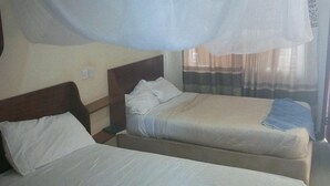 A room with two beds, a wooden headboard, a mosquito net, and a window with curtains. - Kitui Premier Resort (Kitui)