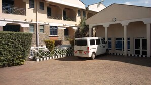 A building with a paved driveway and a white van parked in front. - Kitui Premier Resort (Kitui)