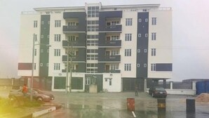 A multi-story residential building with a central staircase, balconies, and a parking area in front. - Bella Residencia (Lekki)