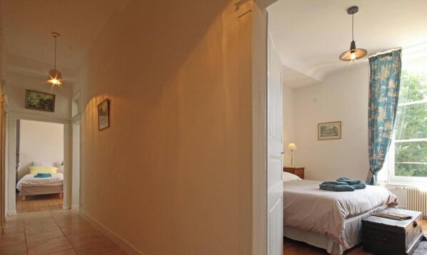 A bedroom with a bed, a nightstand, a lamp, and a window with curtains. - Experience Castle Charm with WiFi in Bellavilliers (Bellavilliers)