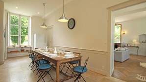 Un coin repas avec une table en bois dressée pour six personnes, entourée de chaises à l’assise rembourrée de tissu bleu.