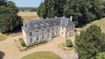 Ein großes, zweistöckiges Steinhaus mit symmetrischer Fassade, zahlreichen Fenstern und einem zentralen Eingang.