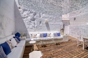Un interior moderno con un sofá blanco, cojines estampados, suelo de madera y un diseño de techo único.
