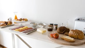 A breakfast buffet with pastries, sandwiches, bread, and condiments on a white countertop. - Hotel Ca s'Arader - Adults Only (Ciutadella de Menorca)