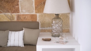 A bed with a headboard, a bedside table with a lamp, a glass, and a small bowl. - Hotel Ca s'Arader - Adults Only (Ciutadella de Menorca)