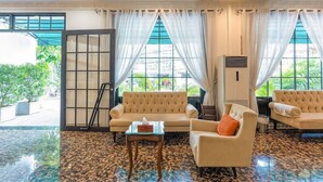 A hotel lobby with a large window, a sofa, a chair, and a small table. - Triip Palago (Ho Chi Minh City)