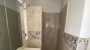 A bathroom with a bathtub, a shower, and tiled walls. - White Decor Penthouse (Lekki)
