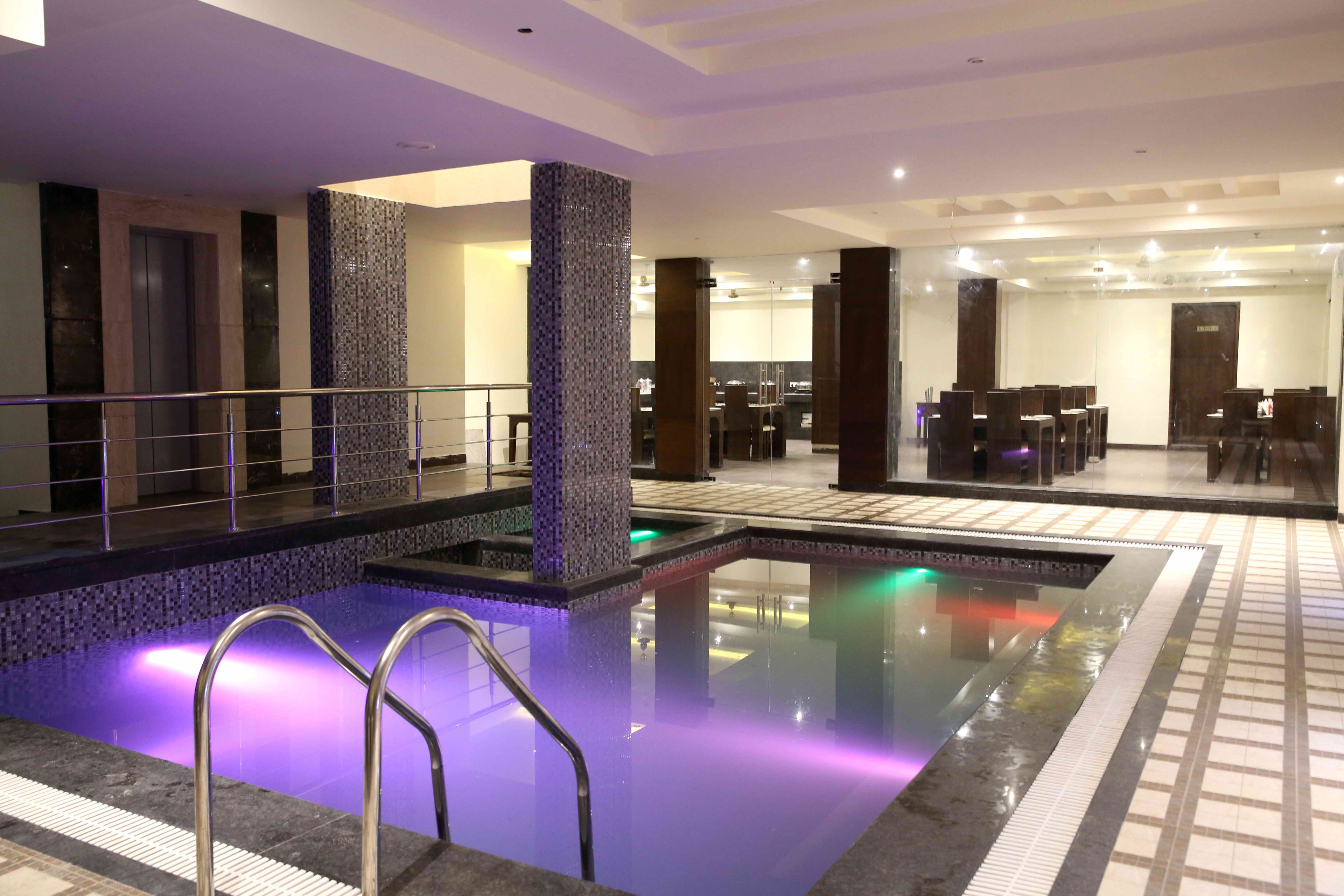 A hotel lobby with a swimming pool, a reception desk, and a dining area.