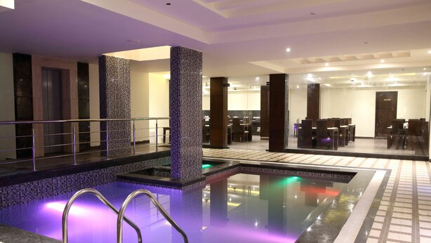 En hotellobby med en swimmingpool, en receptionsdisk och ett område för måltider.