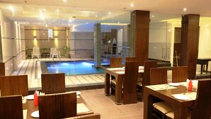 En hotellobby med en pool, ett område för måltider och modern inredning.