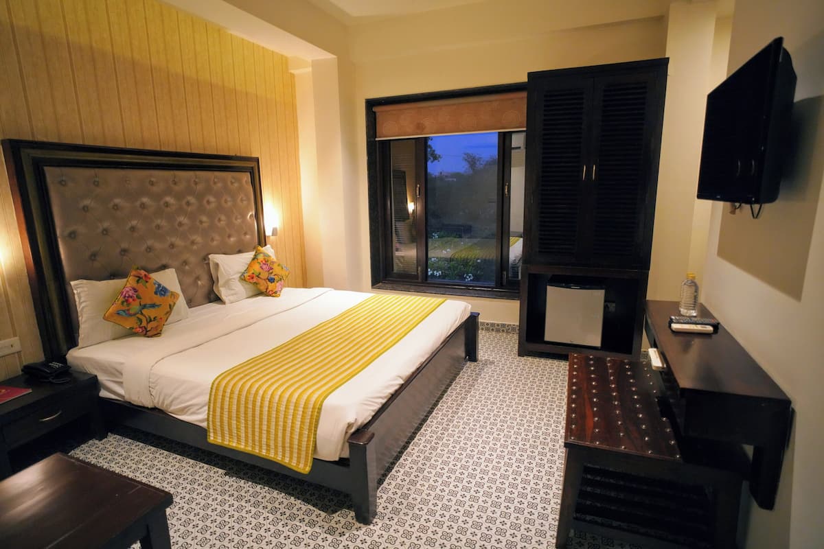 A hotel room with a large bed, bedside table, and a TV mounted on the wall.