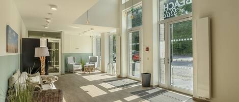 A hotel lobby with a reception desk, seating area, and large windows.