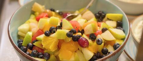 A buffet with a bowl of fruit salad in the foreground.