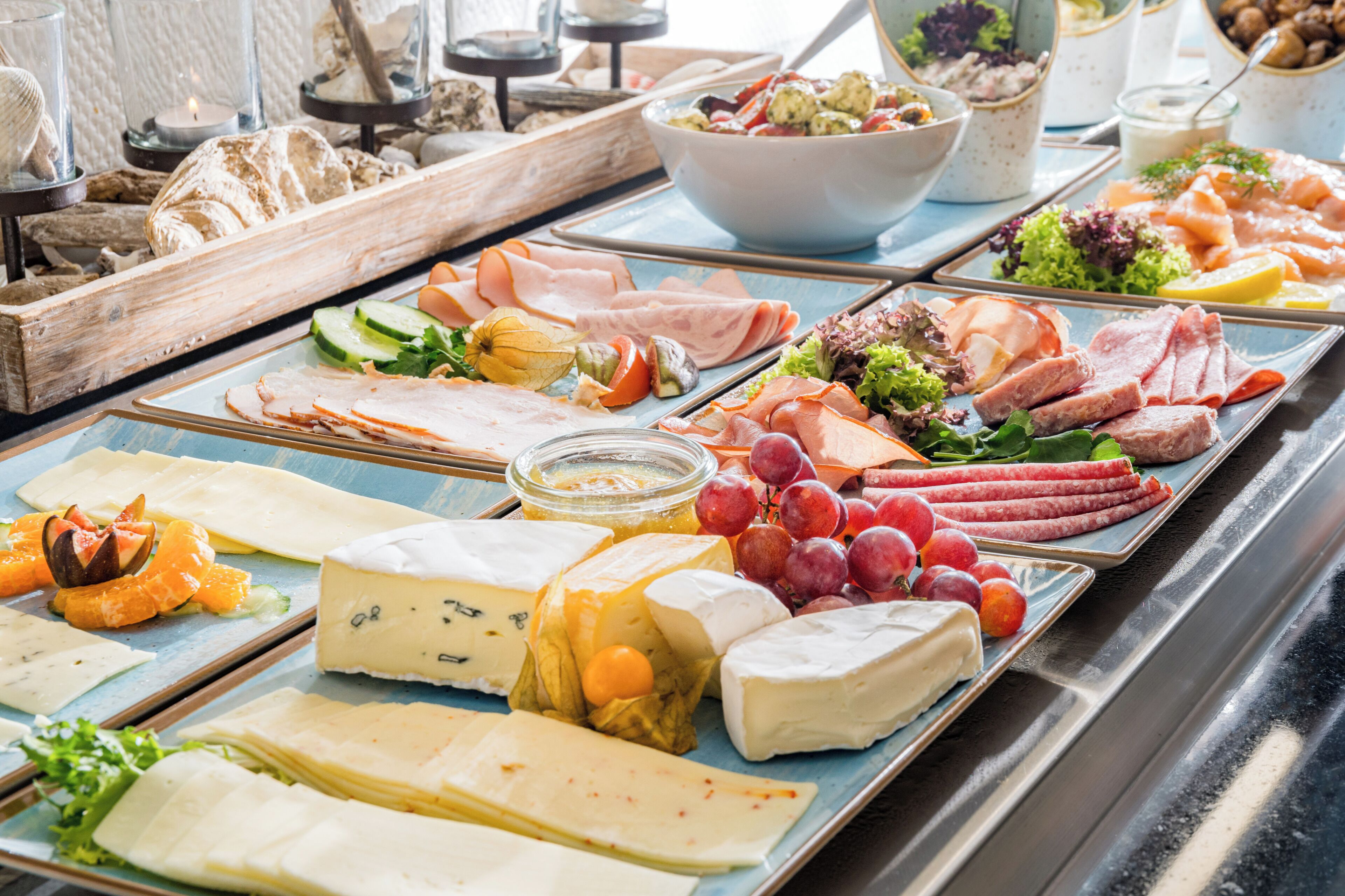 A buffet with various cheeses, meats, and fruits.