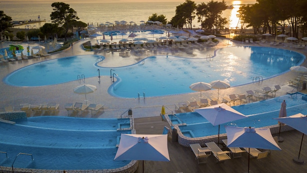 A large, multi-level swimming pool with sun loungers and umbrellas, surrounded by trees and overlooking the sea. - 3 * apartments / 5pax. (Zaton)