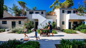 Zona residencial con casas modernas, cielo despejado y una persona empujando un cochecito.