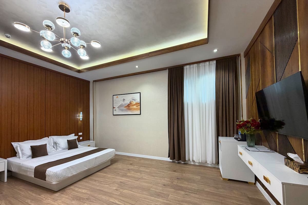 A modern bedroom with a bed, a TV, a desk, and a painting on the wall.