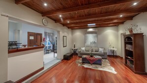 Un salón amplio con suelo de madera, un sofá, una mesa de centro y una estantería.