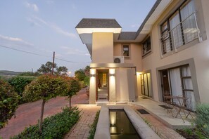 A modern house with a well-lit entrance, a small garden, and a pool.