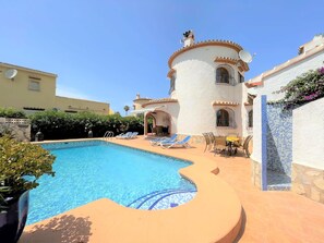 A swimming pool with lounge chairs and a patio area, surrounded by buildings with Mediterranean architecture. - T-0819, Villa Sueños, beautiful villa with mediterranean garden (Alicante)