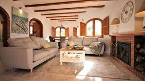 A cozy living room with a fireplace, wooden beams, and comfortable seating. - T-0819, Villa Sueños, beautiful villa with mediterranean garden (Alicante)