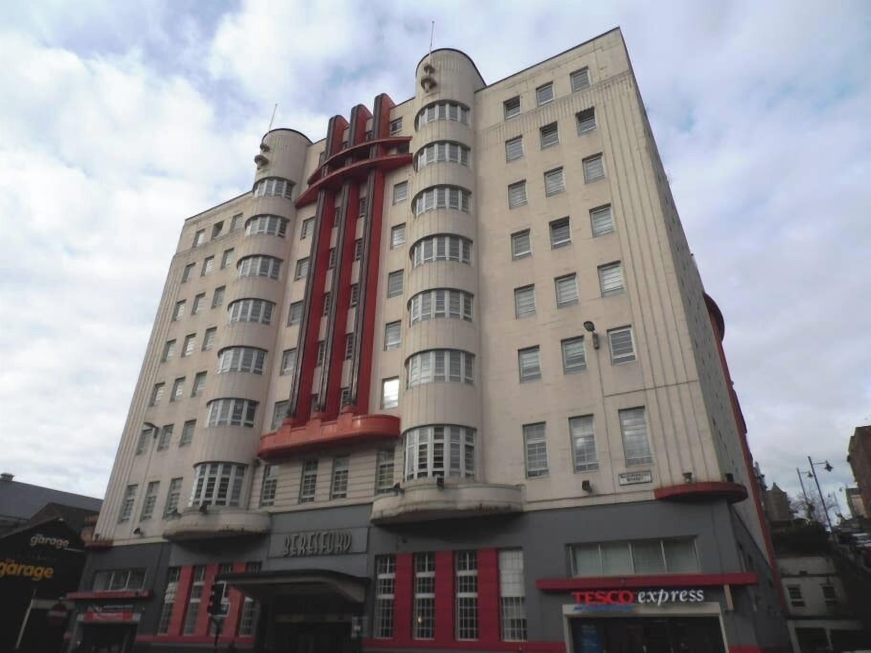 A multi-story building with a distinctive architectural design, featuring curved balconies and a central red structure.