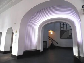 Un couloir doté d’un plafond en arc de cercle, d’un escalier et d’un luminaire fixé au mur.