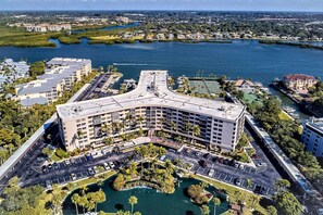 A multi-story hotel with a curved roof, surrounded by parking, a marina, and a body of water. - Resort Style, Heated Pool, Walk to Top Beach (Siesta Key)